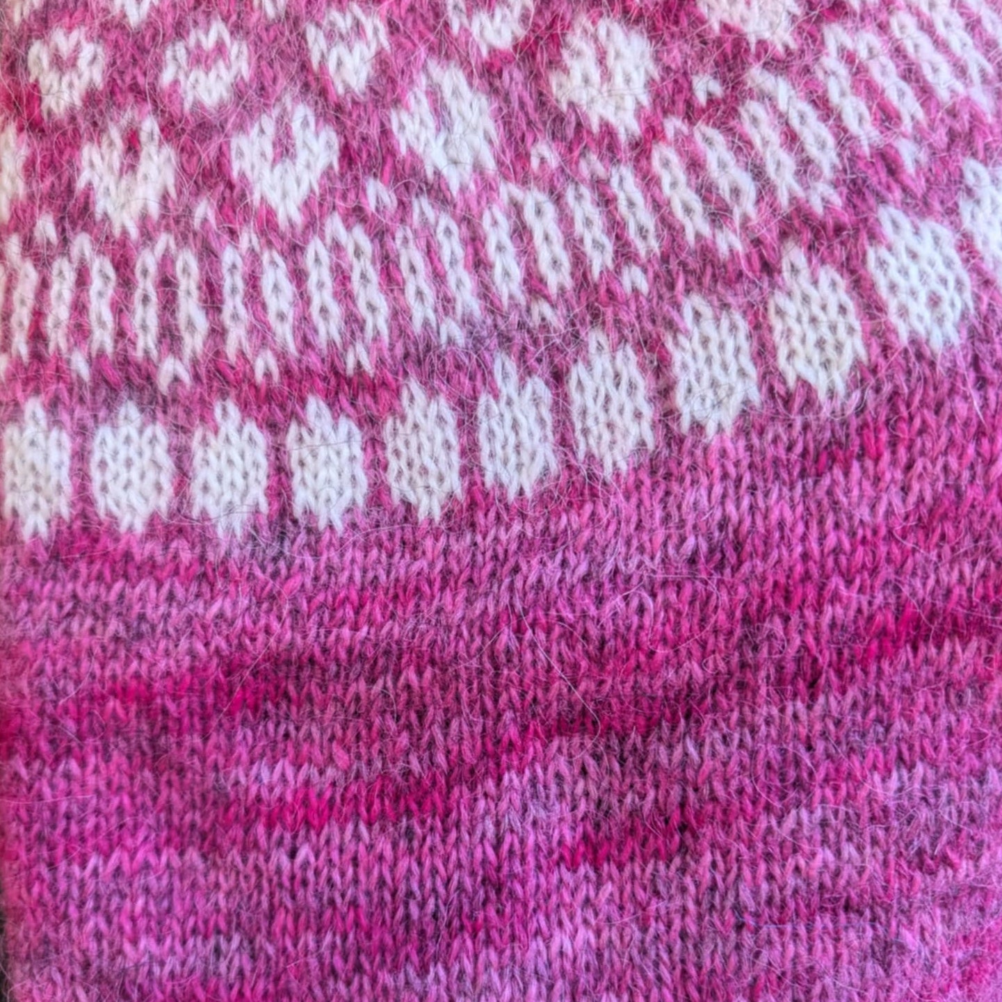 Close-up of knitted Icelandic sweater pattern using hand-dyed lopi yarn in pink tones inspired by garden peony