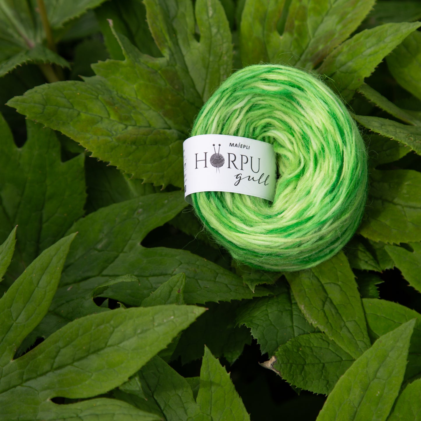 Hand-dyed Icelandic lopi yarn inspired by Himalayan mayapple shown with vibrant green foliage
