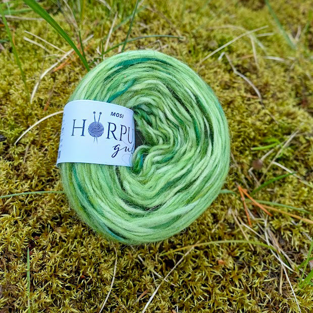 Hand-dyed Icelandic lopi yarn inspired by moss placed on natural moss landscape in Iceland
